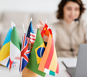 Selective,Focus,Of,Various,International,Flags,Near,Blurred,Laptop,And